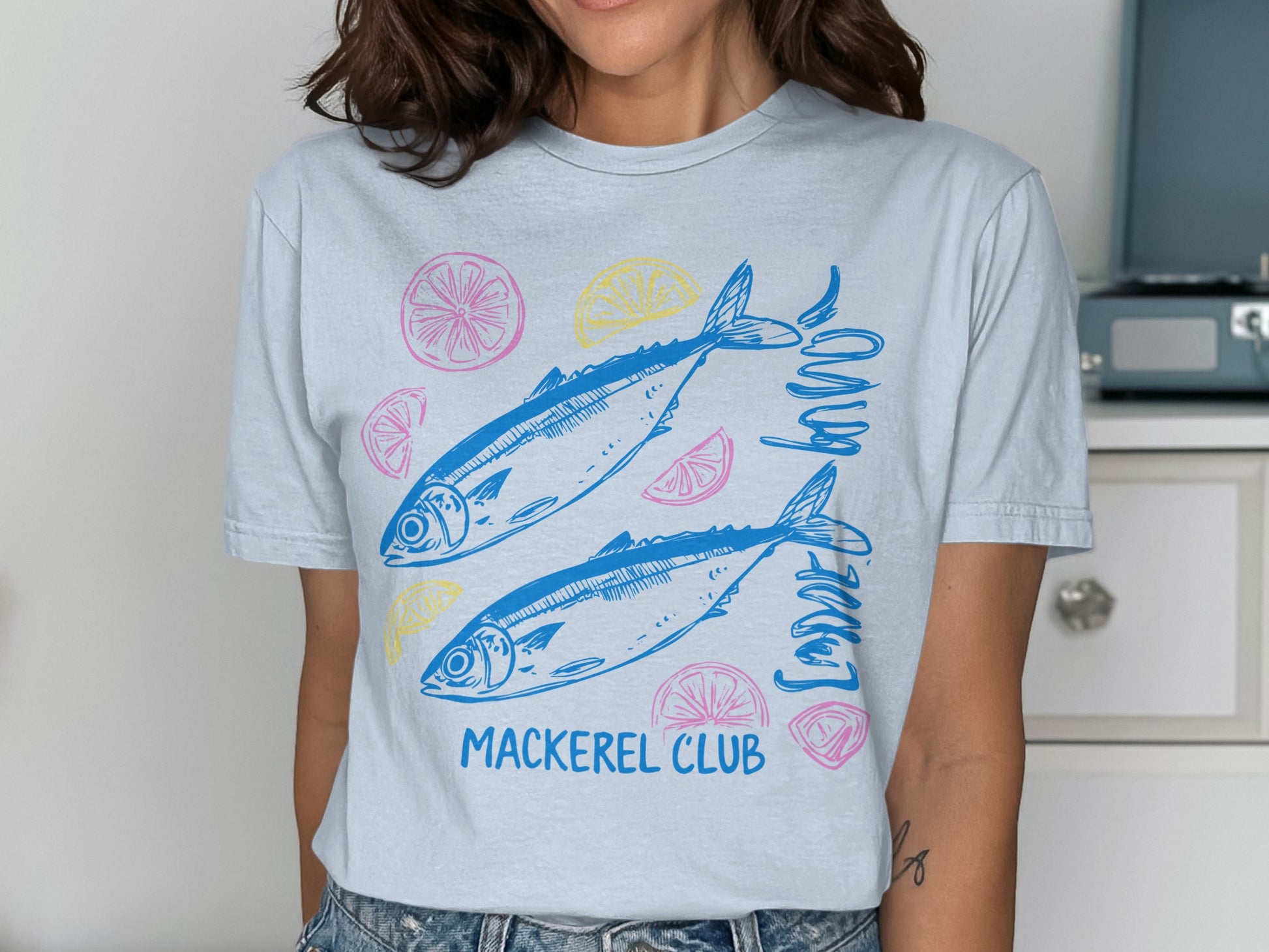 Light blue t-shirt with two blue mackerel and lemon slices, "Mackerel Club" text.