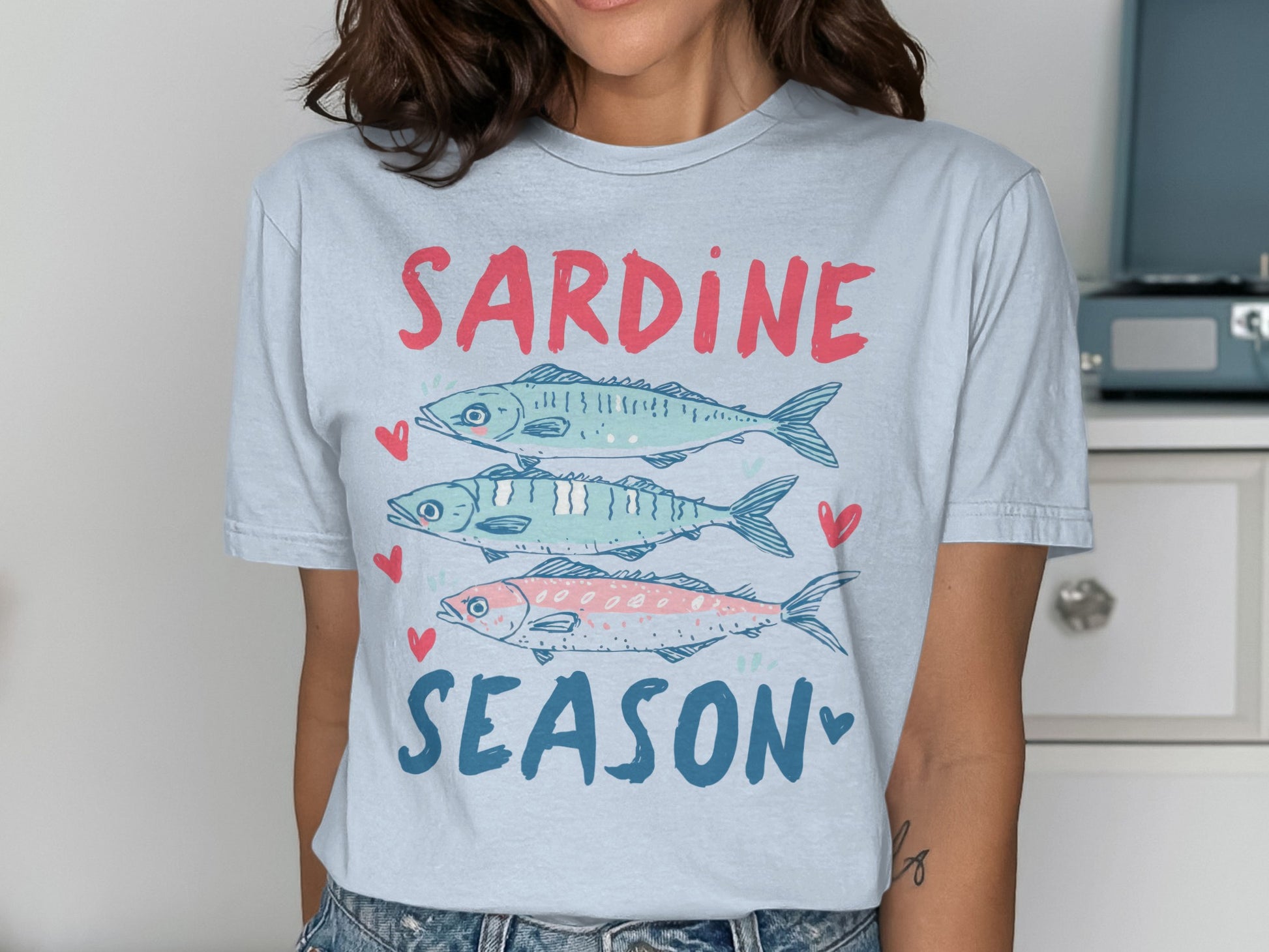 Light blue t-shirt with "SARDINE SEASON" text and three illustrated sardines.