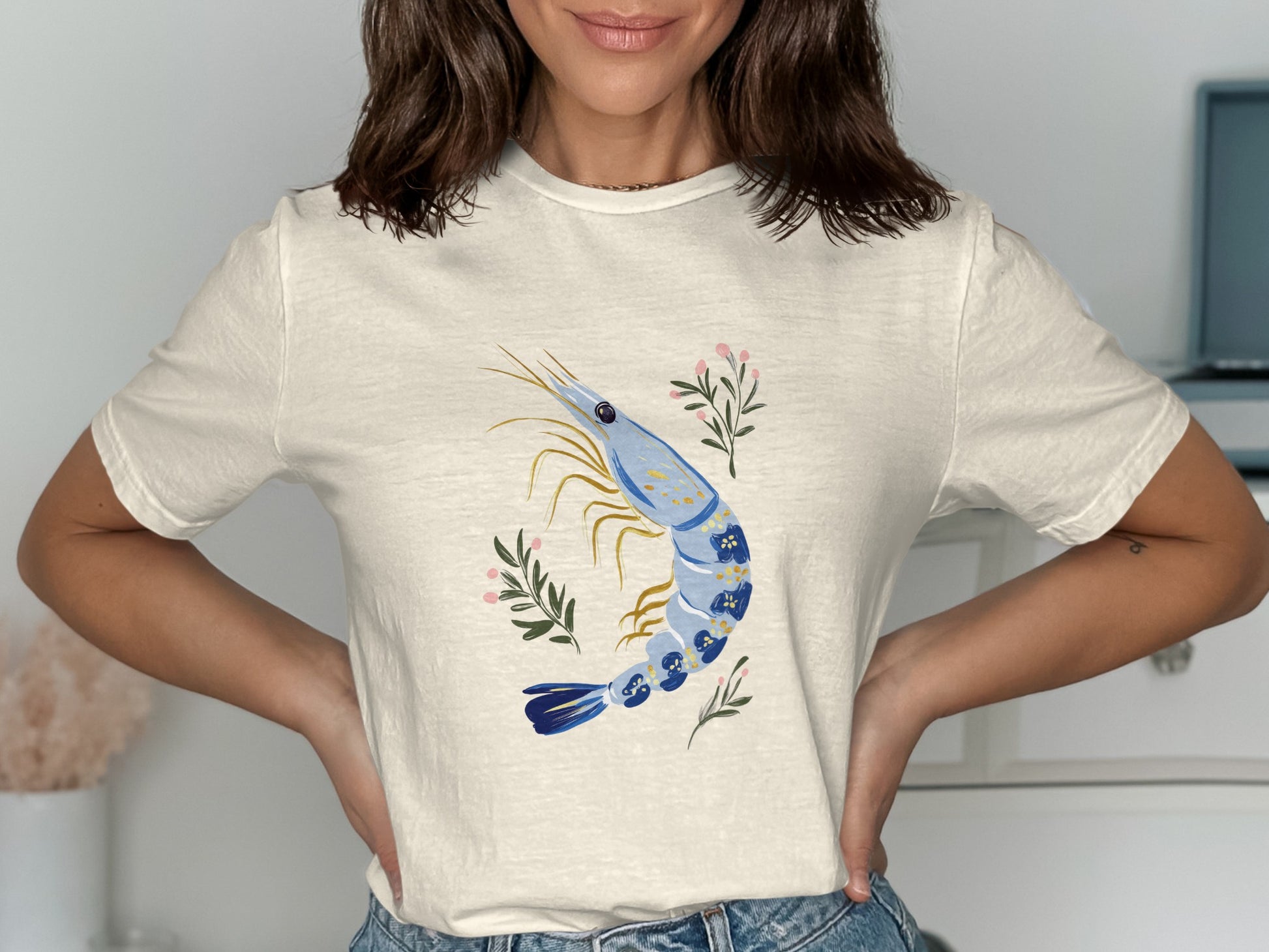 Cream t-shirt with blue shrimp illustration and floral accents.