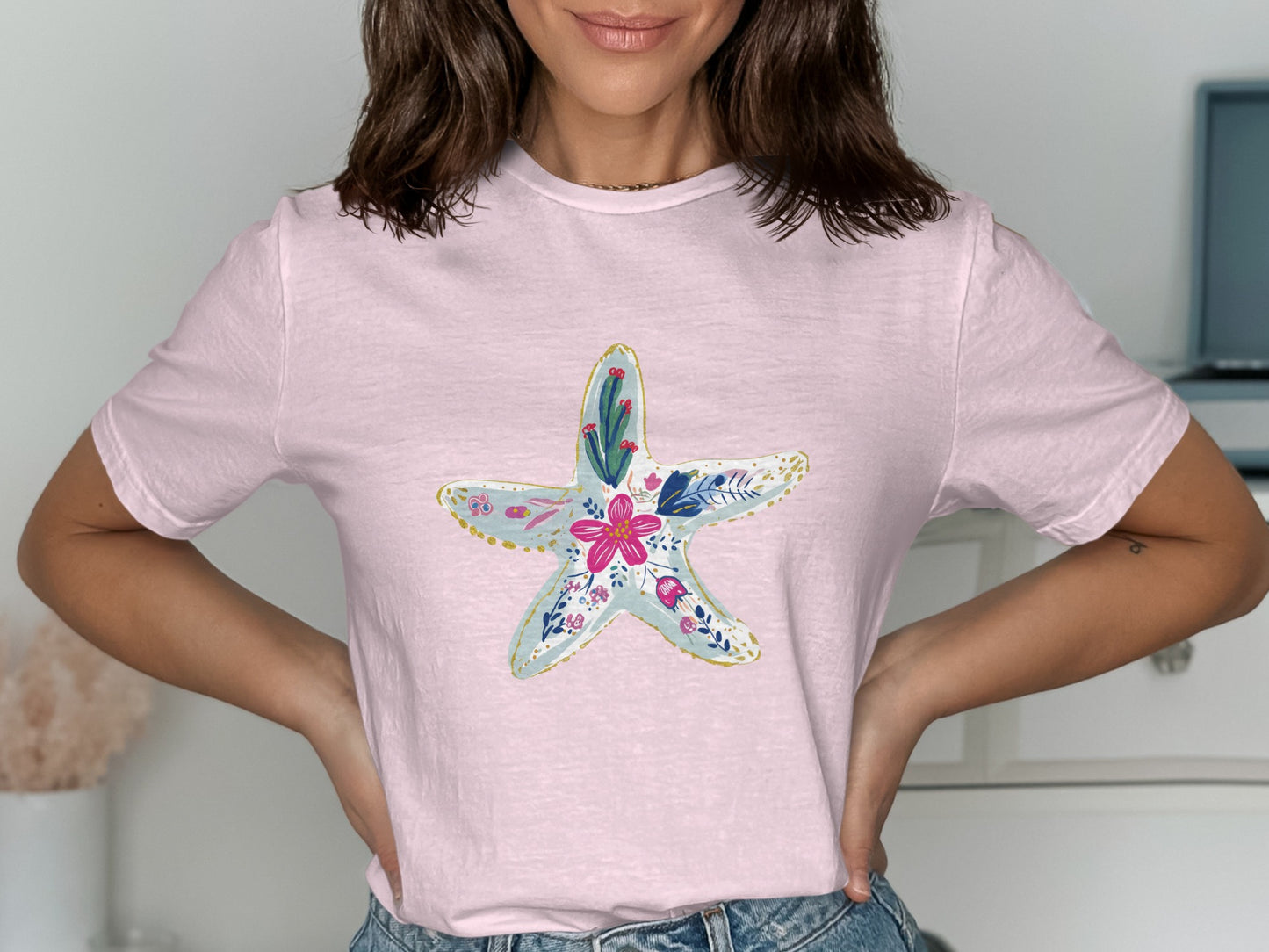 Pink t-shirt with a light blue starfish design featuring floral accents.
