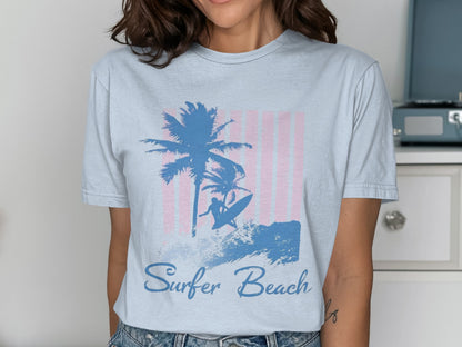 Blue t-shirt with surfer, palm trees, and "Surfer Beach" text on pink stripes.