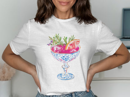 White t-shirt with graphic of pink cocktail in ornate blue and white glass.