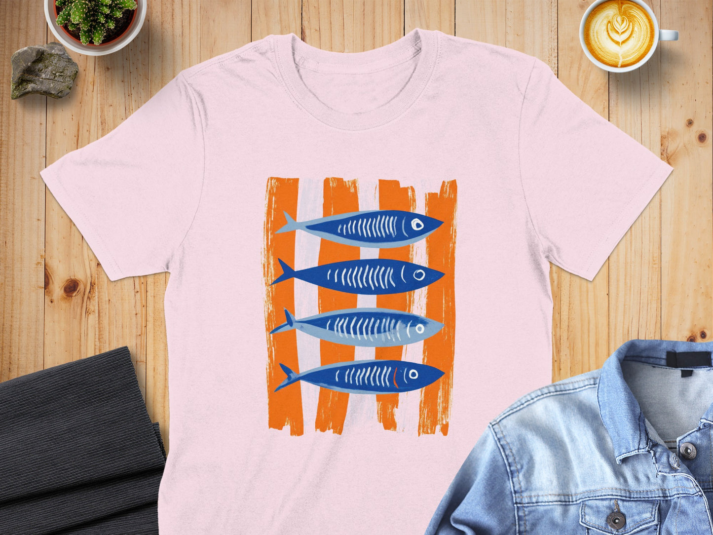 Pink t-shirt with four blue, stylized fish on orange striped background.