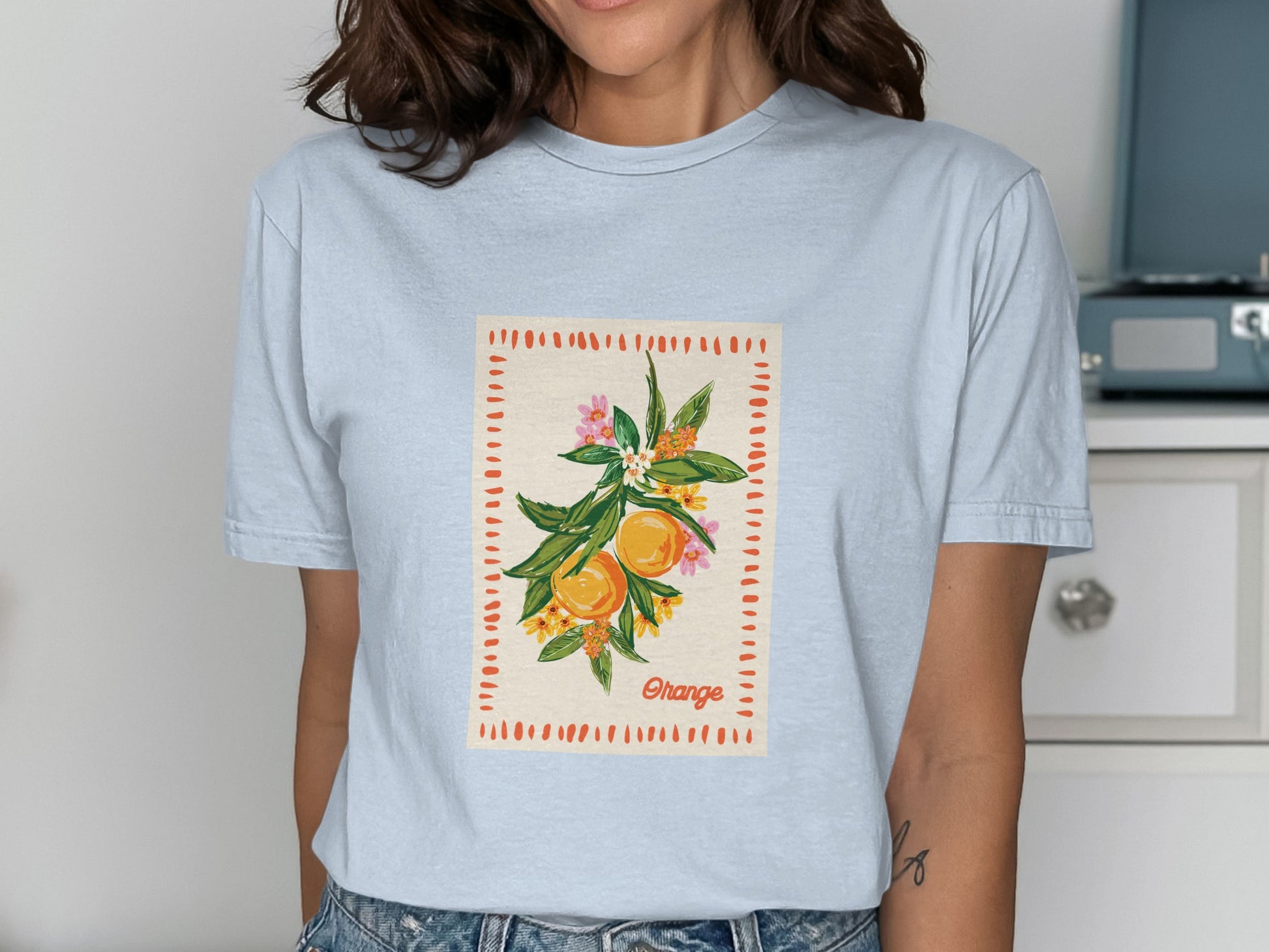 Light blue t-shirt with a graphic of oranges on a branch with flowers and the word "Orange".