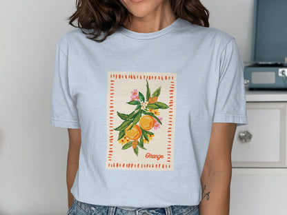 Light blue t-shirt with a graphic of oranges on a branch with flowers and the word "Orange".