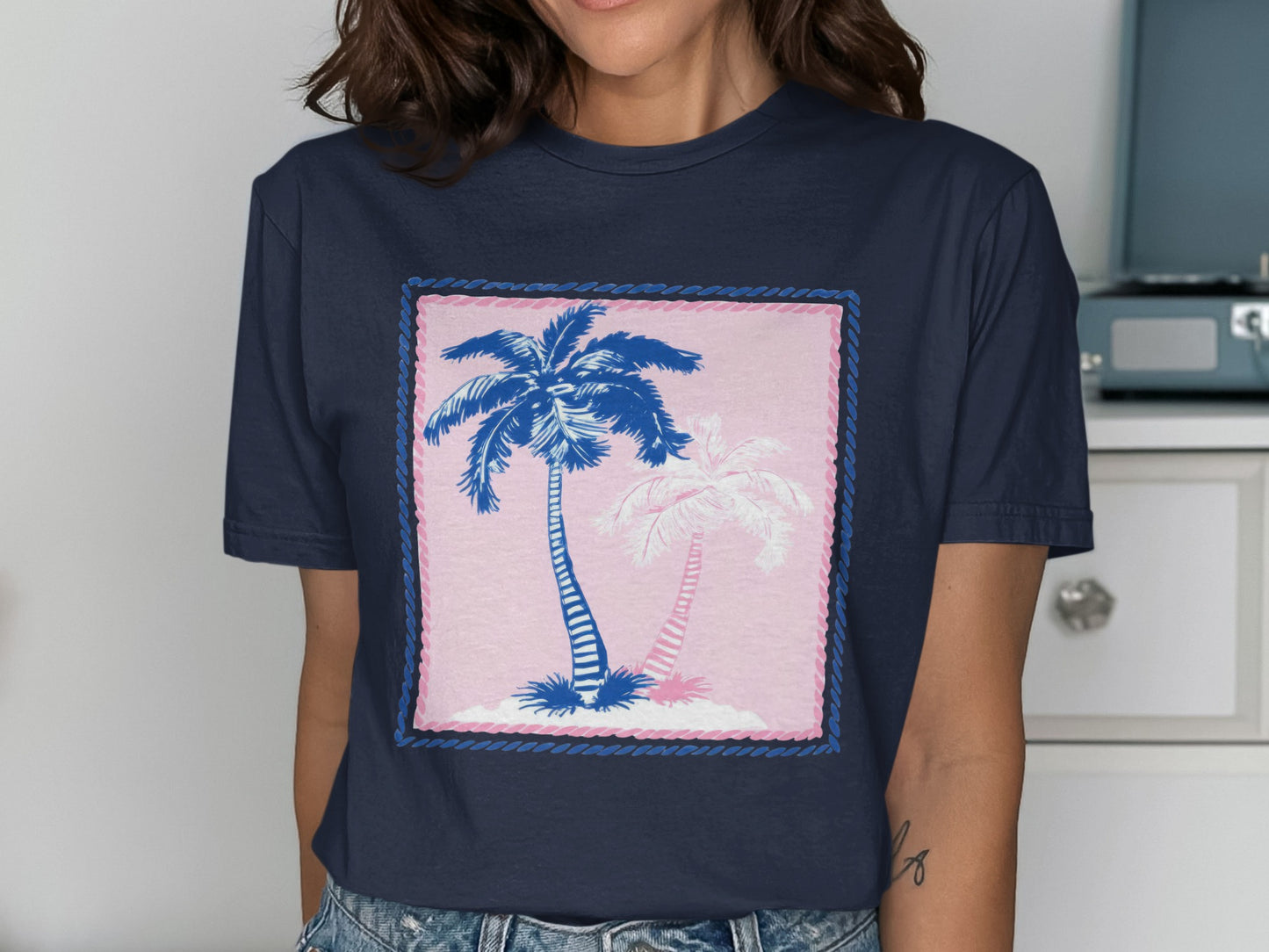 Navy t-shirt with a graphic of two palm trees within a pink and blue border.