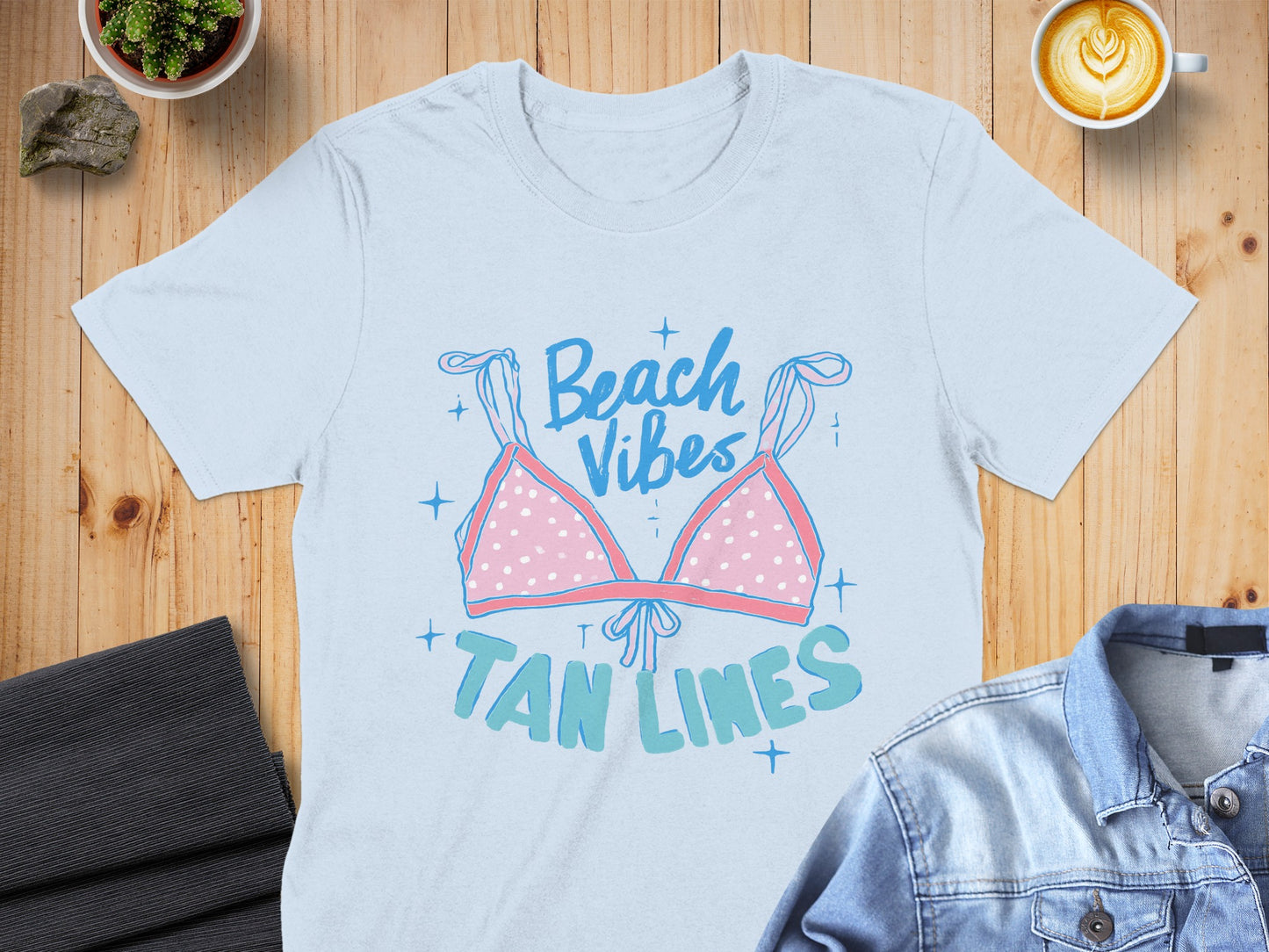 Light blue t-shirt with pink polka dot bikini top graphic and "Beach Vibes Tan Lines" text.