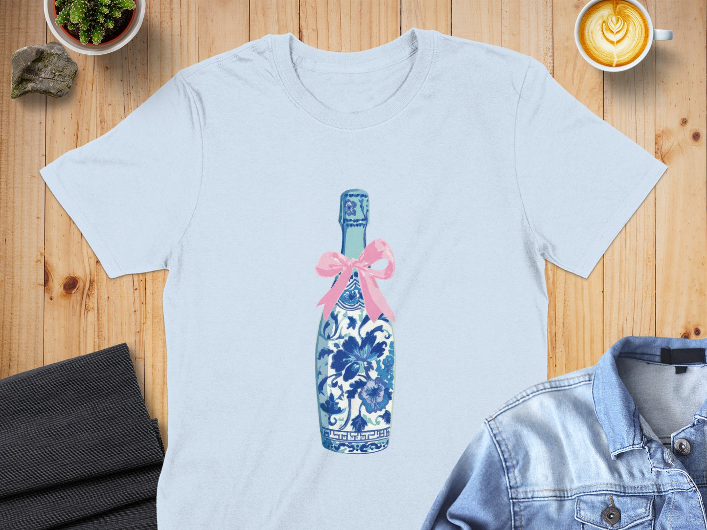 Light blue t-shirt with blue and white porcelain bottle and pink bow graphic.