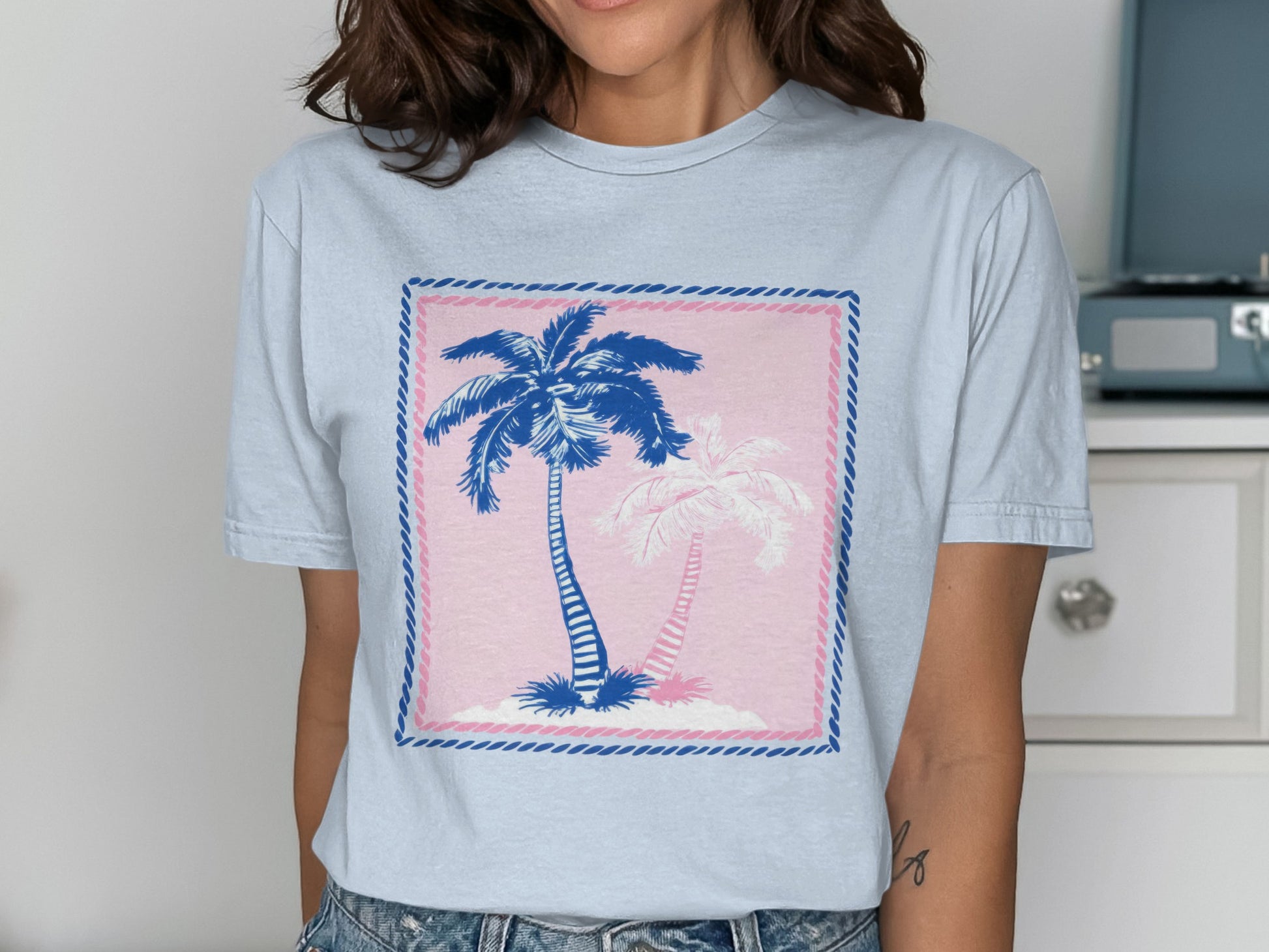 Light blue t-shirt with pink and blue palm trees graphic.