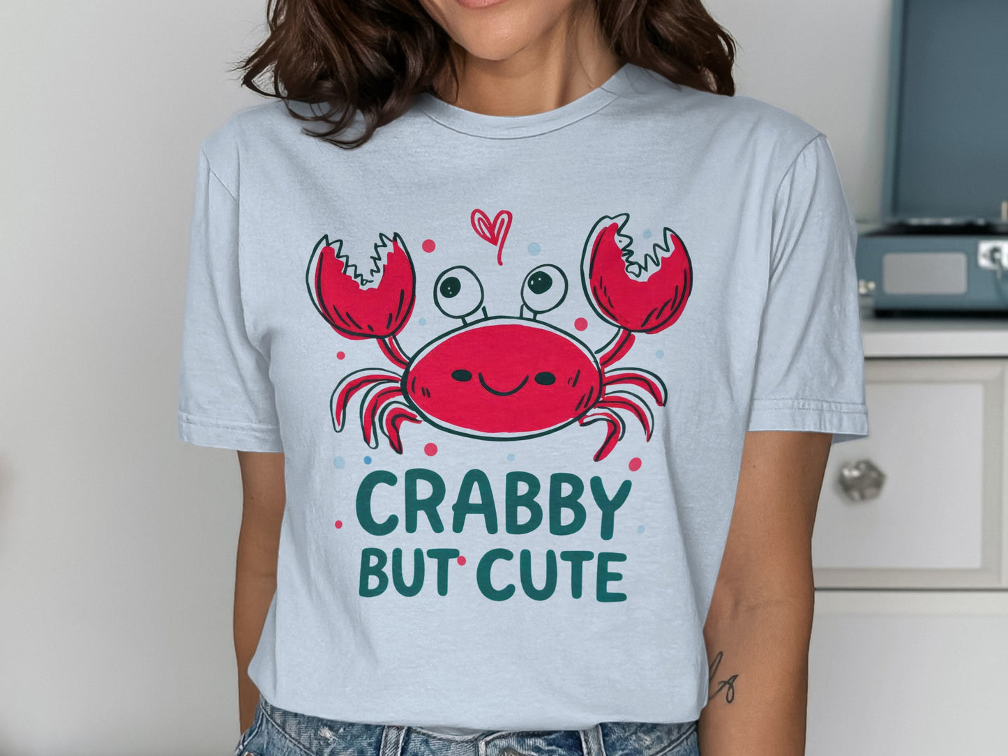 Crabby but cute cartoon crab with hearts on a light blue t-shirt.