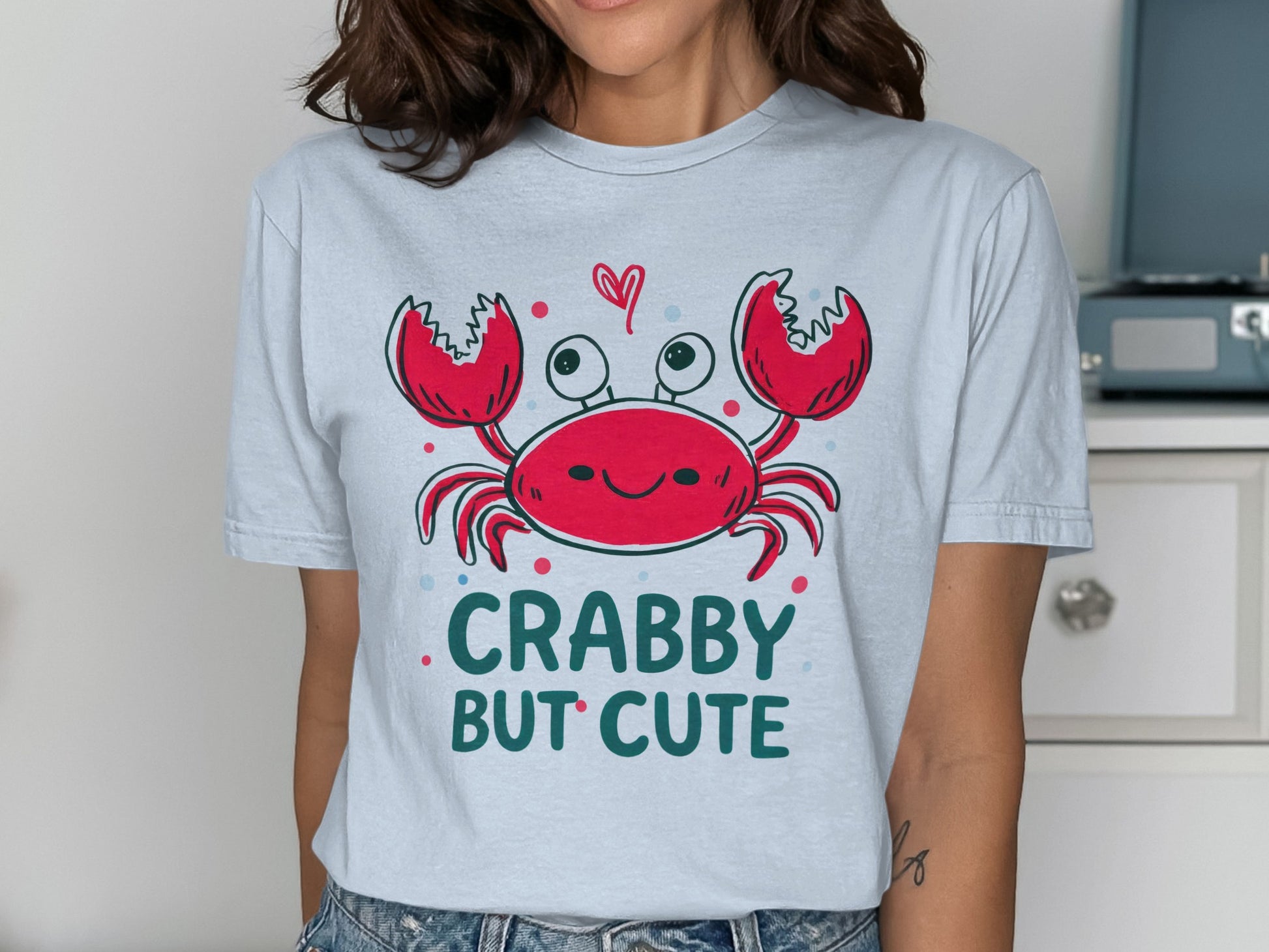 Crabby but cute cartoon crab with hearts on a light blue t-shirt.
